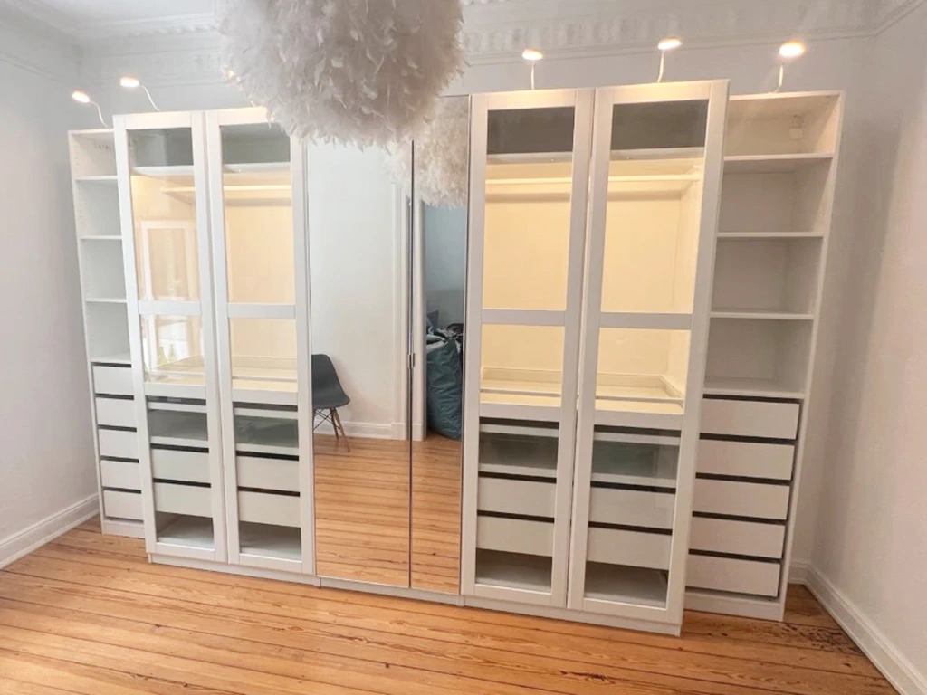 Ein komplett aufgebauter weisser IKEA Wandschrank steht in einer neu bezogenen Wohnung.